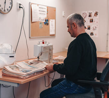Person sitter ved et bord og lager tennbriketter