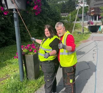 To personer vanner blomster ute i solfylt vær
