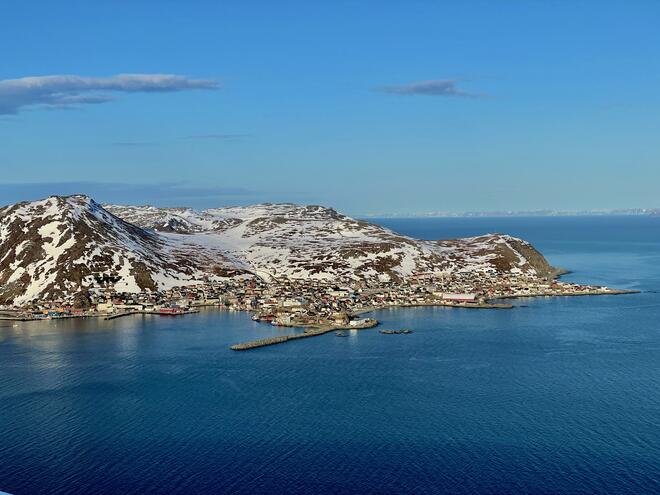 Bilde av Honningsvåg med litt snø på fjellene.